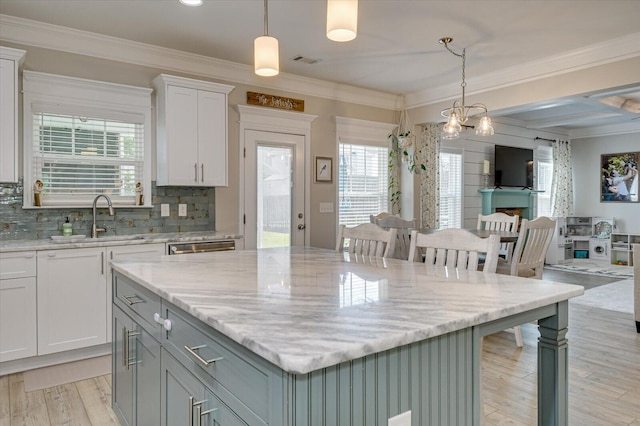 kitchen with white cabinets, a center island, decorative light fixtures, and sink