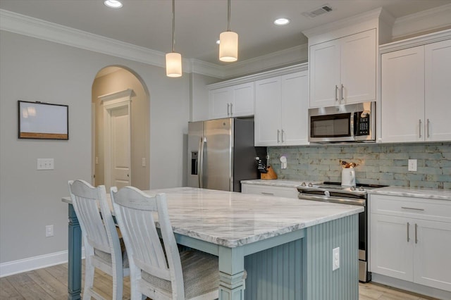 kitchen with a center island, white cabinets, crown molding, hanging light fixtures, and stainless steel appliances