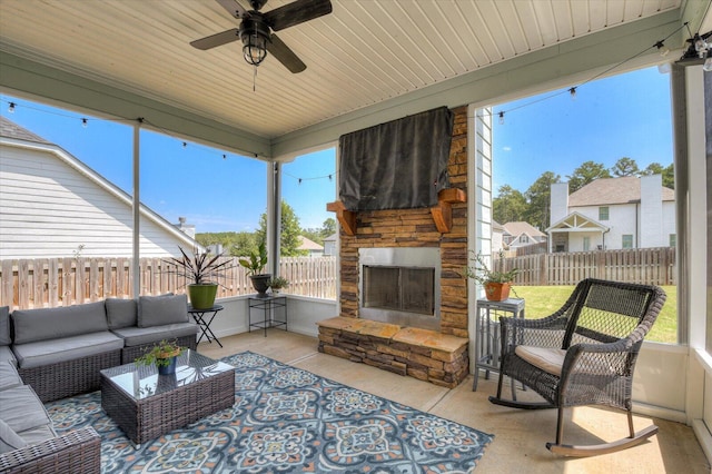 sunroom / solarium with an outdoor stone fireplace, plenty of natural light, and ceiling fan