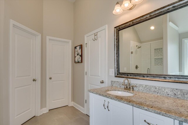 bathroom with tile patterned flooring, vanity, a shower with door, and vaulted ceiling