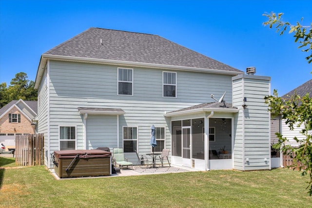 rear view of property featuring a patio area, a sunroom, a yard, and a hot tub