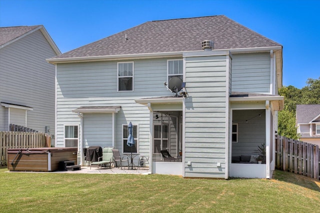 back of house with a lawn, a patio area, a sunroom, and a hot tub