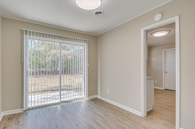 empty room with light hardwood / wood-style flooring, a textured ceiling, and crown molding