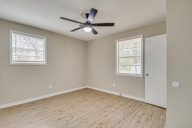 spare room with ceiling fan, a wealth of natural light, and light hardwood / wood-style flooring