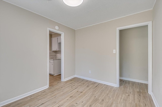 spare room with light hardwood / wood-style floors and a textured ceiling