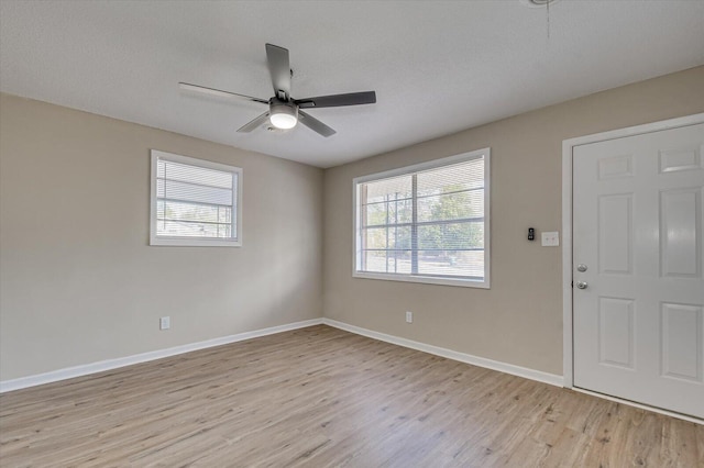 unfurnished room with ceiling fan, a wealth of natural light, light hardwood / wood-style floors, and a textured ceiling