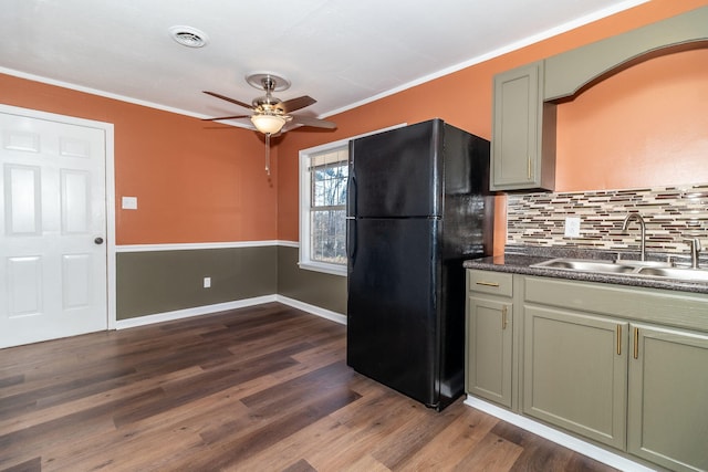 kitchen with black refrigerator, tasteful backsplash, sink, ornamental molding, and dark wood-type flooring