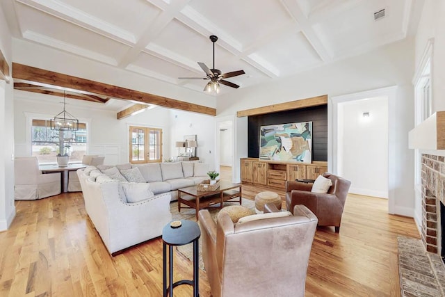 living room featuring beam ceiling, light wood finished floors, visible vents, a brick fireplace, and coffered ceiling