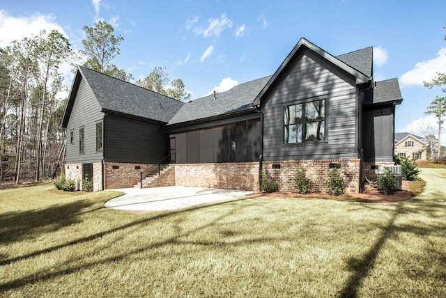 view of side of property featuring brick siding, a yard, a sunroom, a patio area, and cooling unit