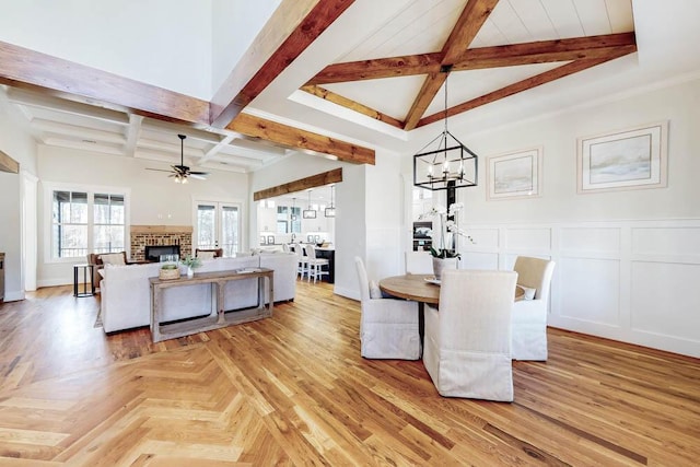 dining space featuring coffered ceiling, a brick fireplace, a decorative wall, beam ceiling, and ceiling fan with notable chandelier