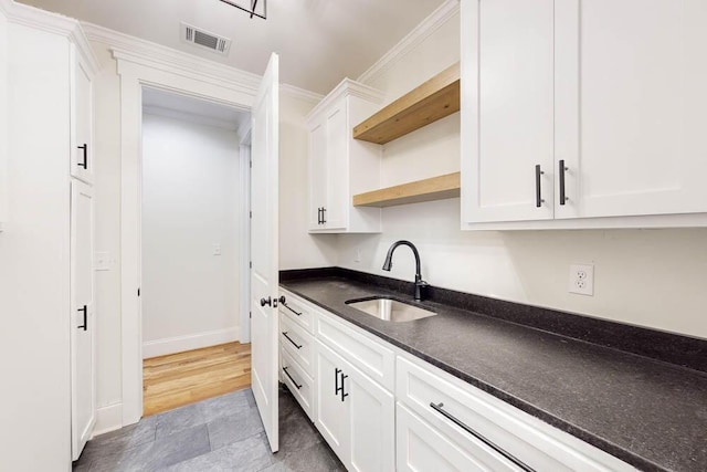 kitchen featuring a sink, visible vents, white cabinetry, open shelves, and crown molding