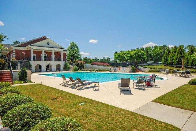 pool with a patio area, fence, and a lawn