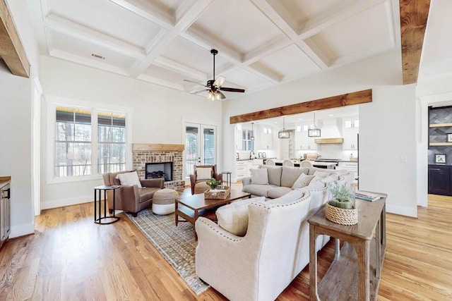 living room featuring a brick fireplace, a healthy amount of sunlight, and light wood-style flooring