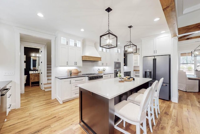 kitchen featuring appliances with stainless steel finishes, light wood-type flooring, a kitchen island, and custom range hood