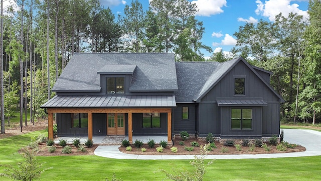 modern farmhouse style home featuring a standing seam roof, a front lawn, a porch, and board and batten siding