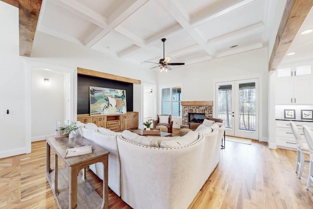 living room with baseboards, coffered ceiling, light wood-style flooring, beamed ceiling, and a brick fireplace