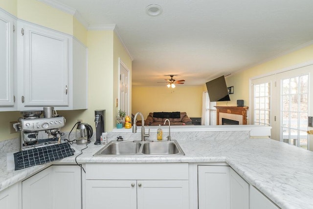 kitchen featuring sink, white cabinetry, ornamental molding, kitchen peninsula, and ceiling fan