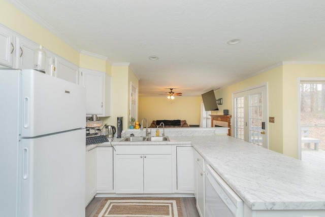 kitchen with sink, white appliances, ornamental molding, white cabinets, and kitchen peninsula