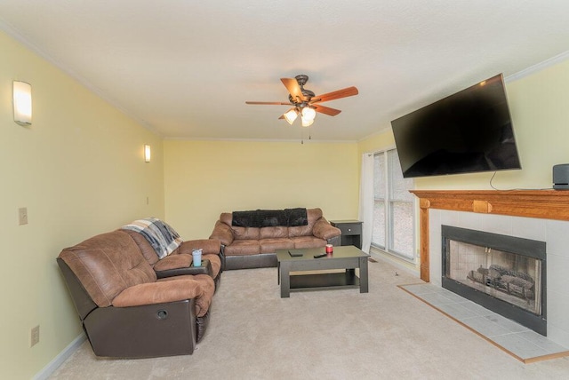 carpeted living room with a tiled fireplace, ornamental molding, and ceiling fan