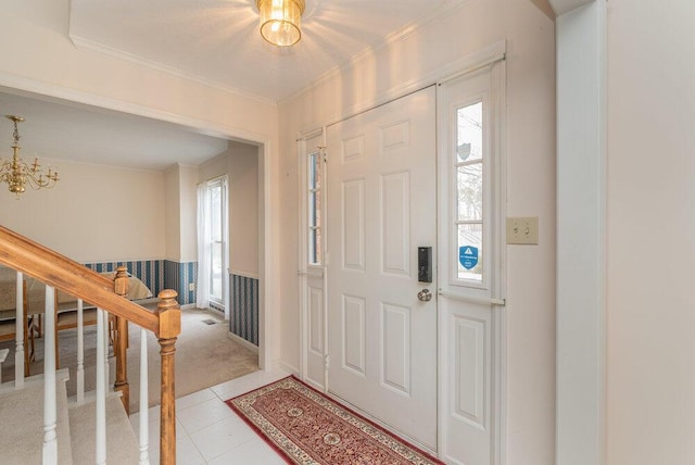 tiled entrance foyer featuring ornamental molding, plenty of natural light, and a notable chandelier