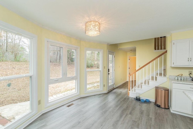 interior space with a notable chandelier, crown molding, and light wood-type flooring