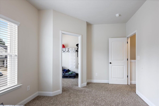 unfurnished bedroom with carpet, baseboards, and a walk in closet