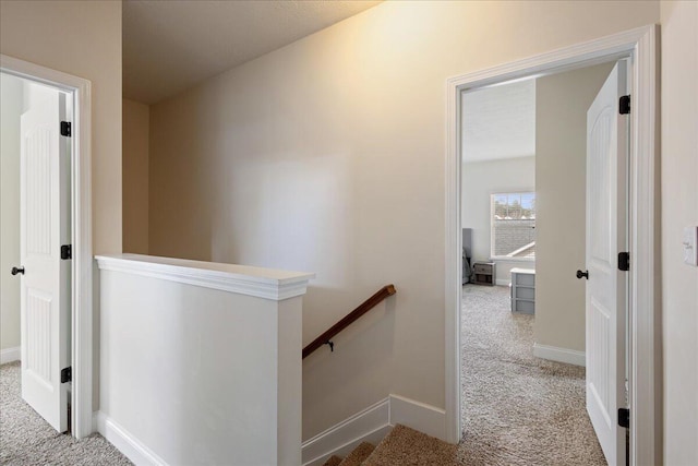 corridor featuring baseboards, carpet flooring, and an upstairs landing