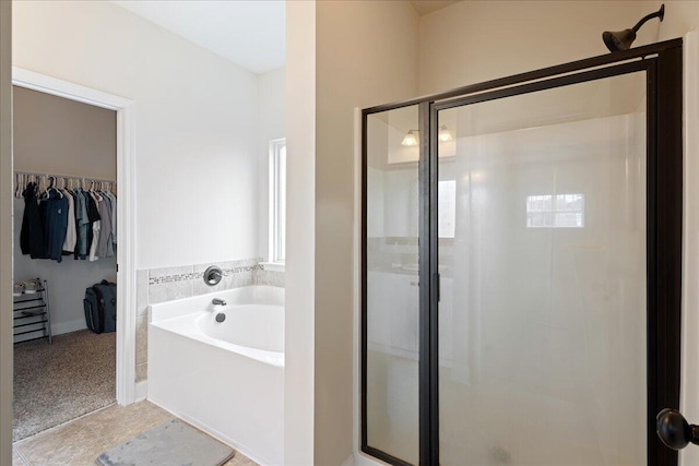 full bathroom featuring a stall shower, a spacious closet, and a bath