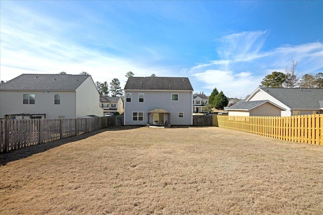 rear view of house with a fenced backyard and a yard