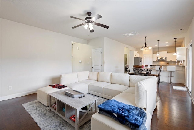 living room with dark wood-style floors, a ceiling fan, and baseboards