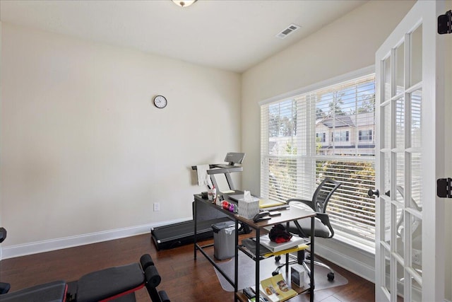 exercise room with wood finished floors, visible vents, and baseboards