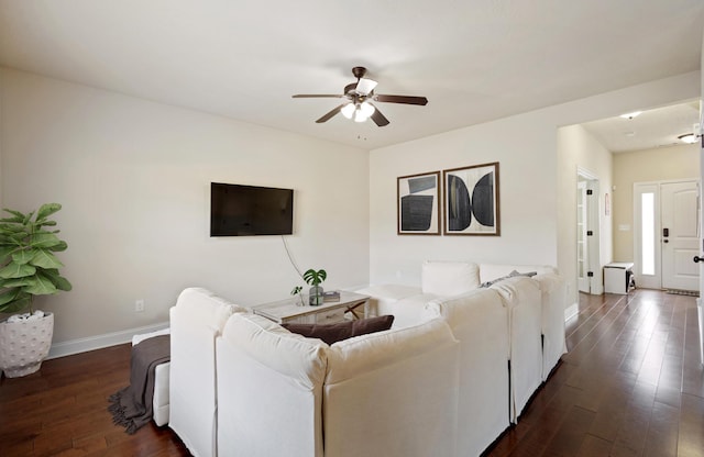 living area featuring dark wood-type flooring, a ceiling fan, and baseboards