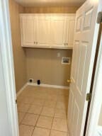 clothes washing area with cabinets, hookup for a washing machine, and light tile patterned floors