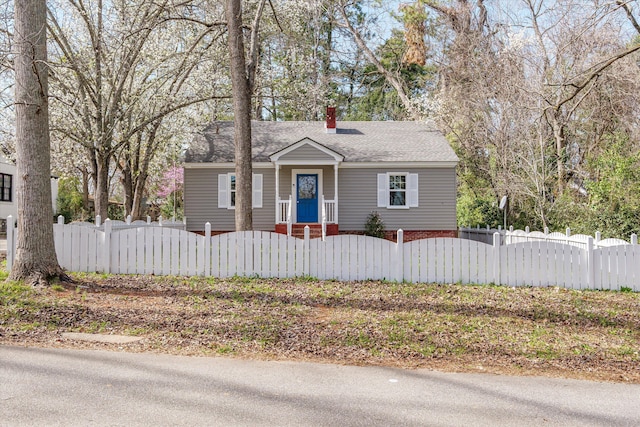 bungalow featuring a fenced front yard, a chimney, and a shingled roof