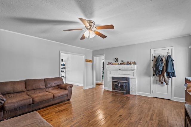 102 Oak St, Washington, GA 30673 - living area with a textured ceiling, hardwood / wood-style floors, baseboards, a brick fireplace, and ceiling fan