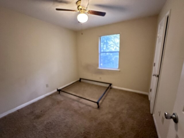 unfurnished room featuring ceiling fan and dark carpet