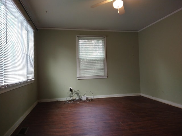 spare room with dark wood-type flooring, a healthy amount of sunlight, ornamental molding, and ceiling fan