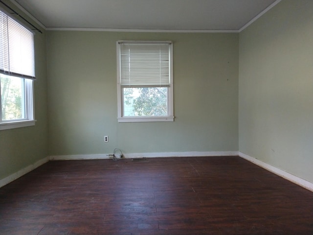 empty room with crown molding, a healthy amount of sunlight, and dark wood-type flooring