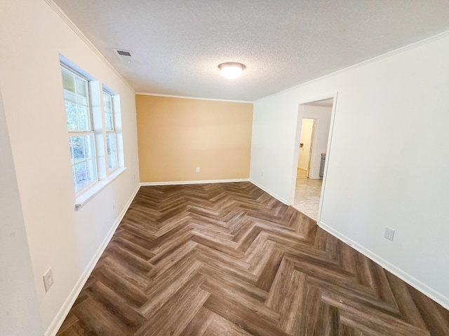 spare room with parquet flooring, a textured ceiling, and crown molding