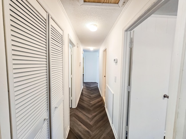 hallway featuring dark parquet flooring, crown molding, and a textured ceiling