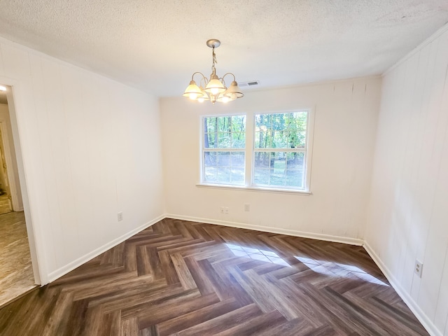 spare room featuring a notable chandelier, a textured ceiling, and dark parquet floors