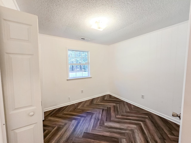 spare room featuring dark parquet flooring and a textured ceiling