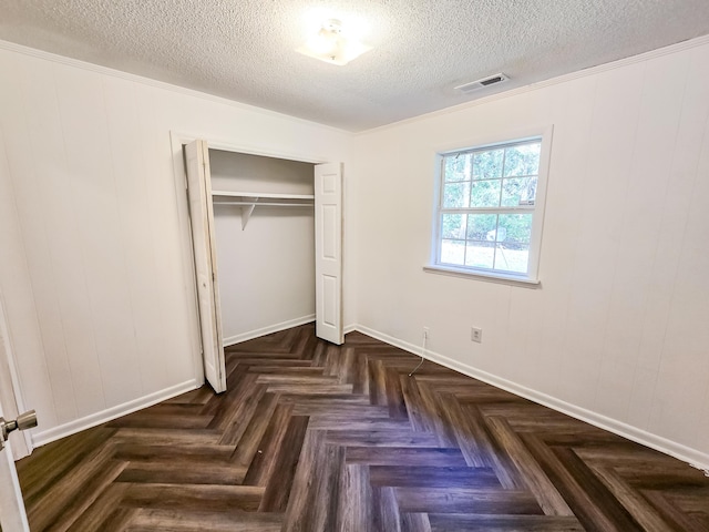 unfurnished bedroom with a textured ceiling, dark parquet floors, a closet, and ornamental molding