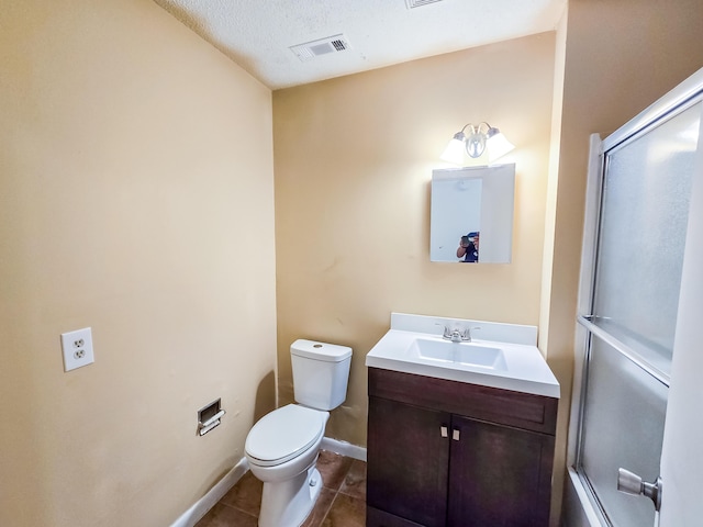 bathroom with vanity, a shower with door, tile patterned floors, toilet, and a textured ceiling