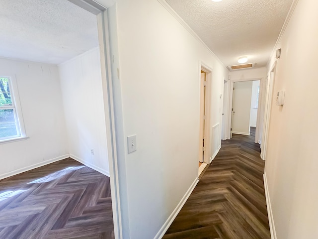 corridor featuring dark parquet floors, ornamental molding, and a textured ceiling