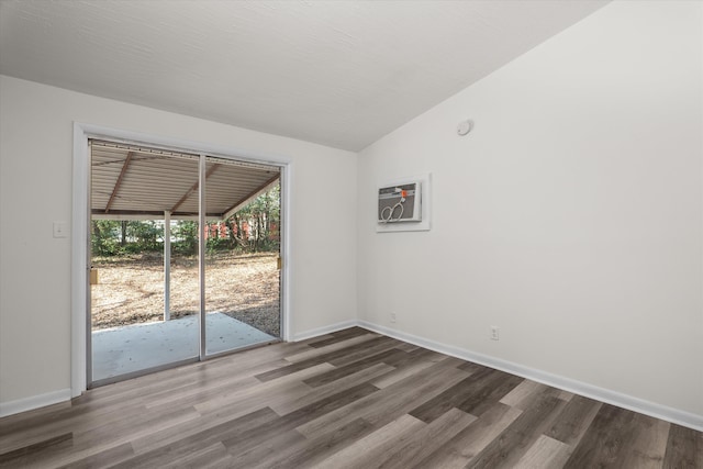 spare room with lofted ceiling, a wall mounted air conditioner, and hardwood / wood-style flooring