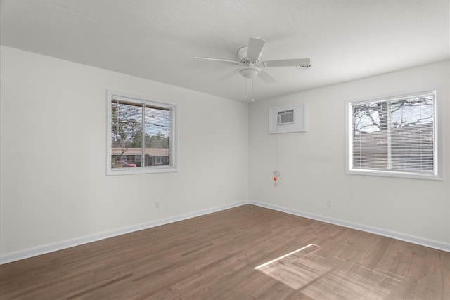 unfurnished room with ceiling fan, a wall mounted air conditioner, and hardwood / wood-style floors