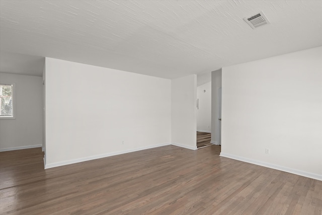 unfurnished room with dark wood-type flooring and a textured ceiling