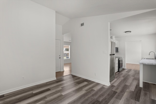 unfurnished living room featuring dark hardwood / wood-style flooring, sink, and vaulted ceiling