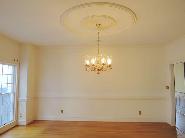 unfurnished room featuring crown molding, an inviting chandelier, and wood-type flooring